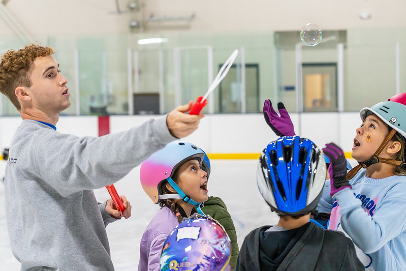 Camp counselor blowing bubbles while skaters try to catch them.