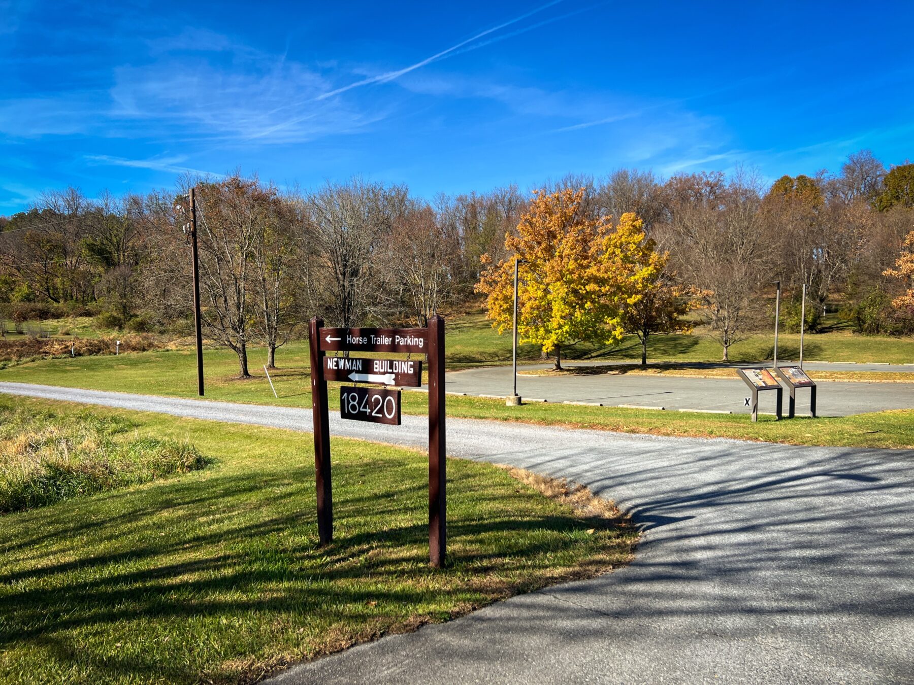 The brown wood sign directing to "horse trailer parking" and the "Newman Building" and the address number 18420