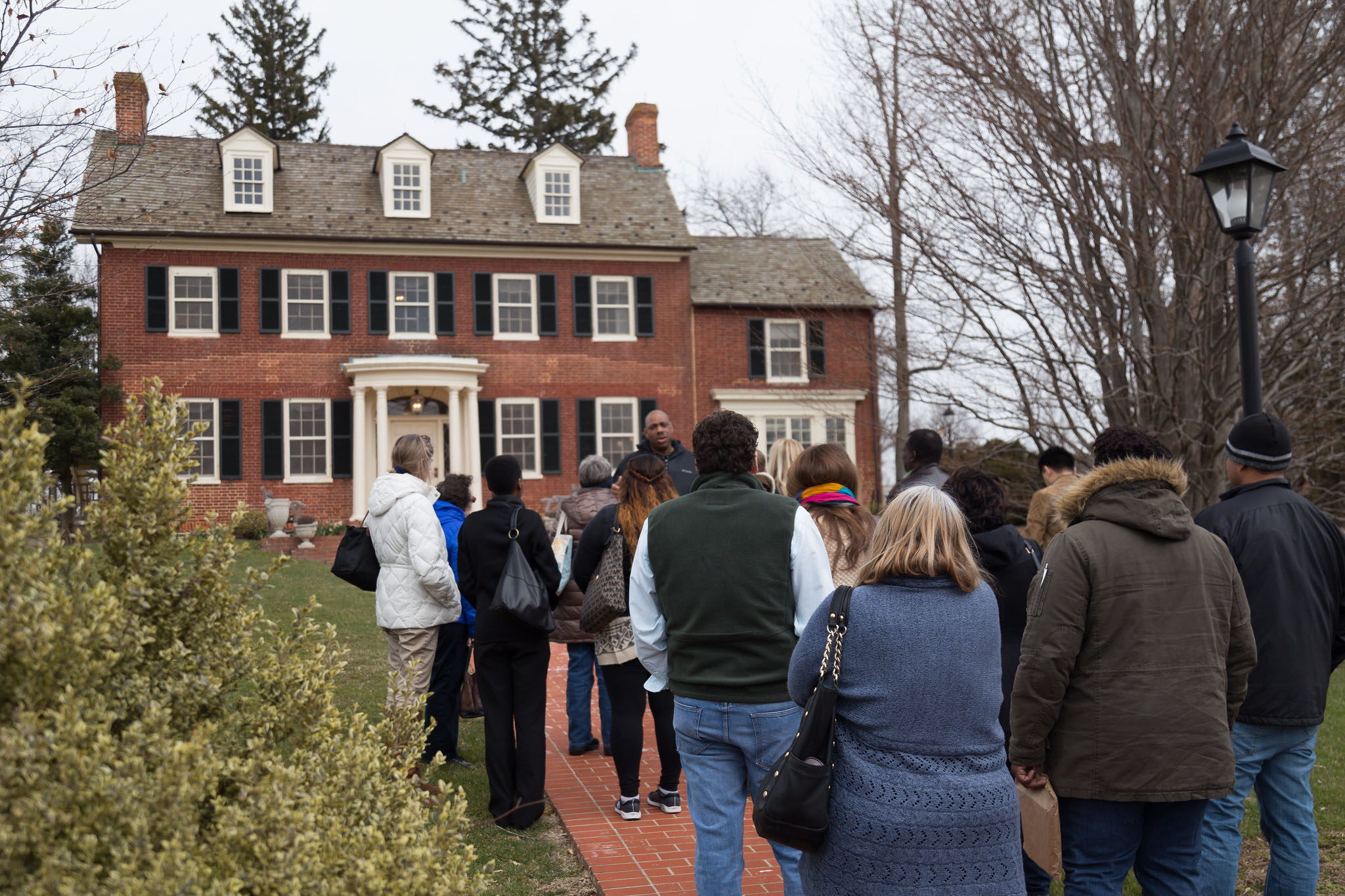 Group tours Woodlawn Manor House, visitors outside the front door. 