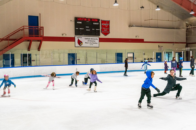 Skating coach showing young skaters how to perform a lunge