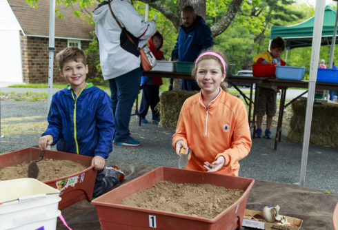 Children in front of dirt piles on archaeology day