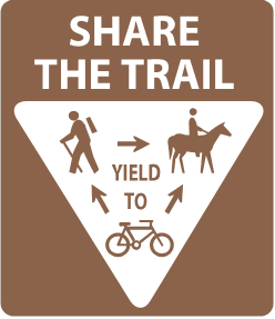 Brown and white sign showing the required yielding for trail users: Bikers should yield to hikers and horses. Bikers and Hikers should yield to horses at all times.