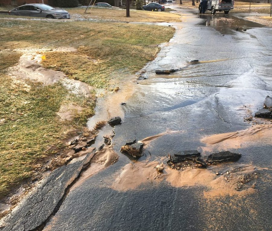 Water and sediment on a lawn near a road after water line break. 