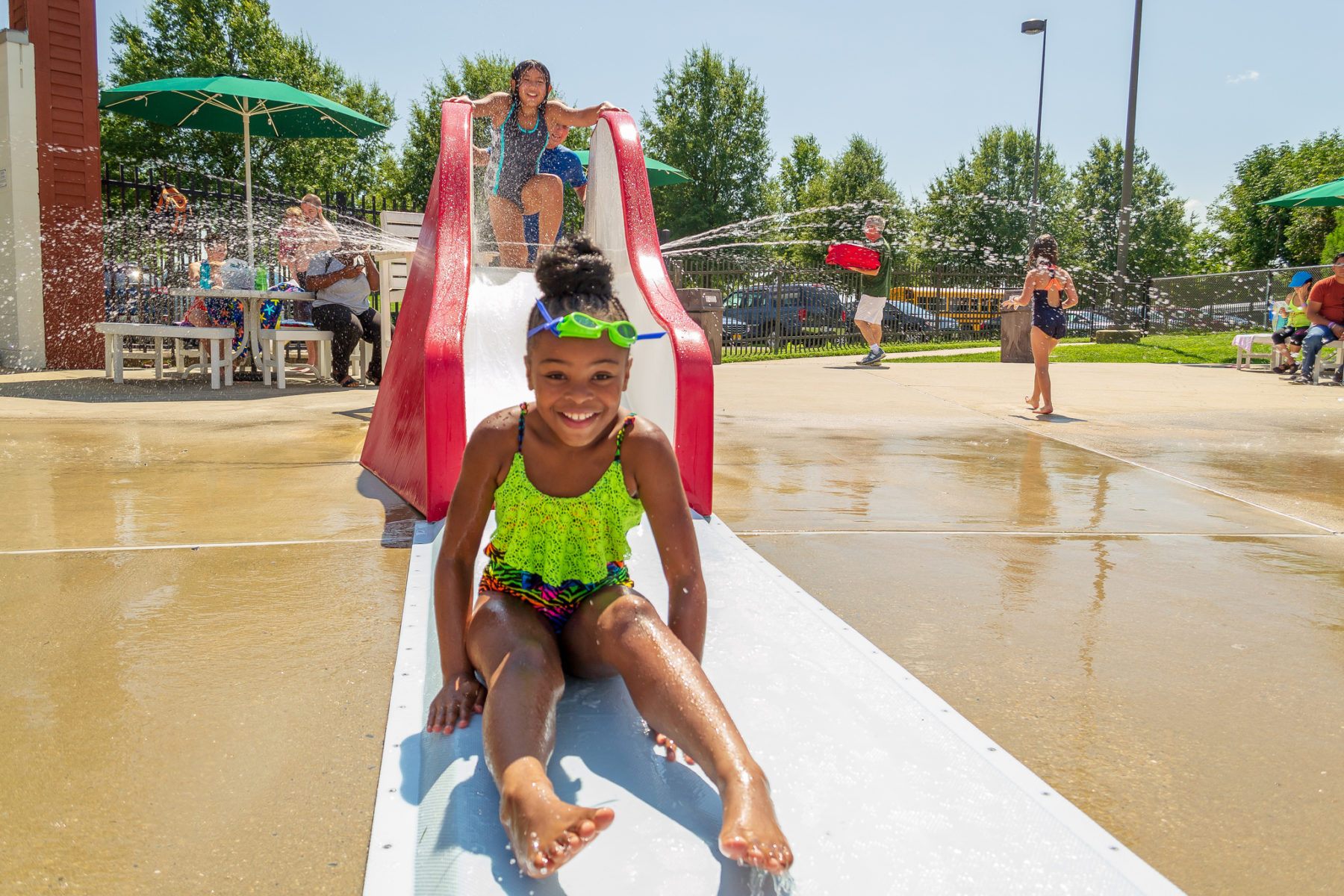 A girl smiles after going down a small slide at the South Germantown SplashPark