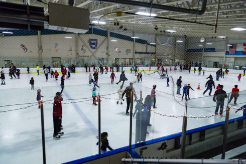 Adults and children ice skating during a public skating session at one of Montgomery Parks' indoor ice rinks. 