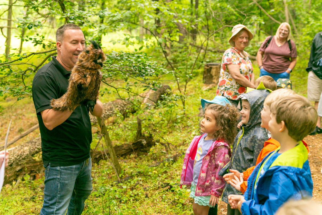 Children watching park naturalist holding owl puppet