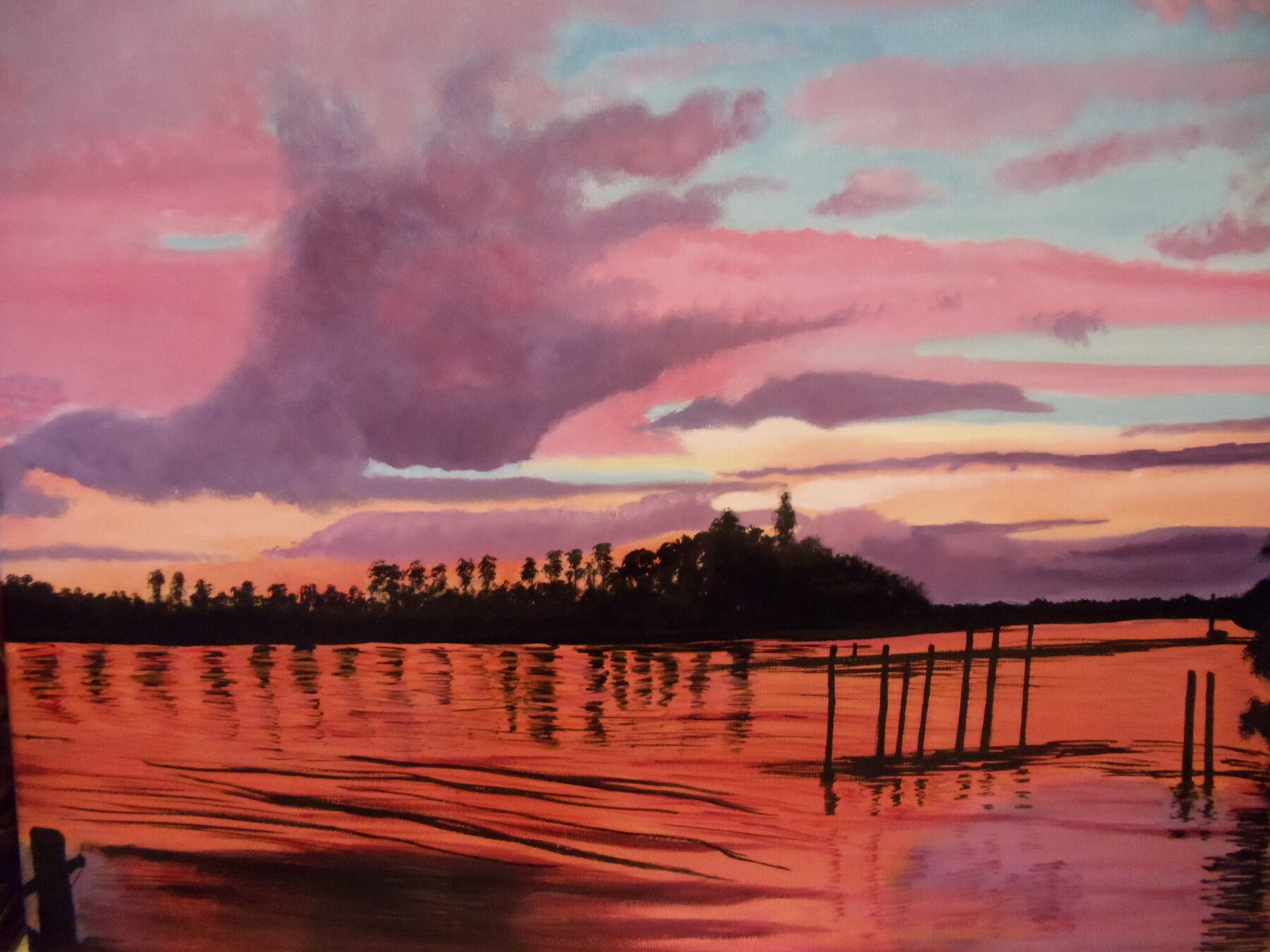 Painting of a tranquil waterscape at sunset, with pink and purple clouds stretching across the sky and their colors reflected on the water below. A tree-lined shoreline appears in silhouette on the horizon, and several wooden posts stand in the water in the foreground, creating a peaceful, reflective scene.