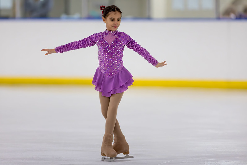 Girl in magenta dress doing a t-stop in the ice show