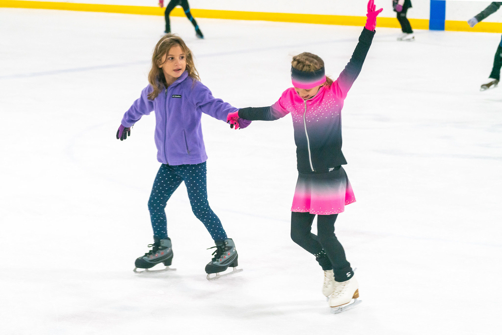 two kids holding hands ice skating