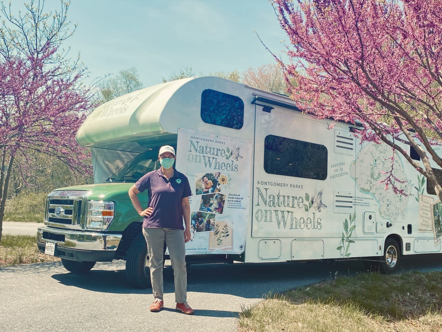 A naturalist stands in front of the Nature on Wheels RV