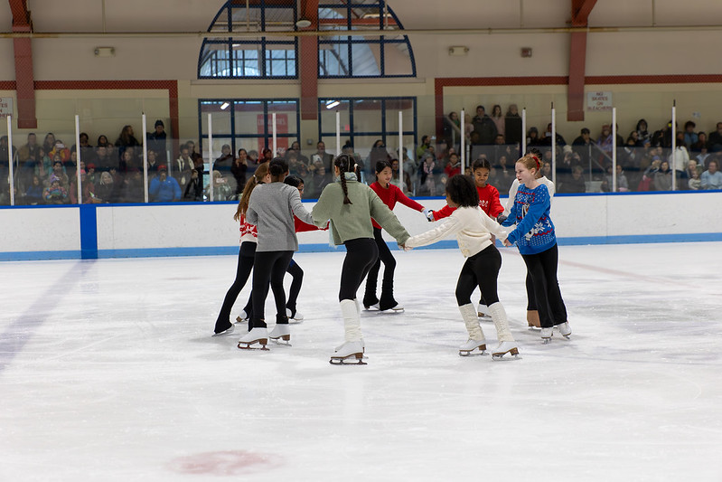 Skaters skating in a circle holding hands during the ice show