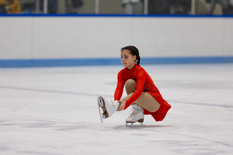 Skater in red dress performing a shoot the duck in the ice show