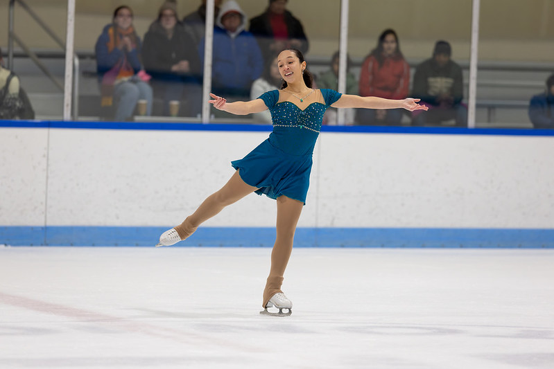 Skater in teal dress performing an arabesque in the ice show.