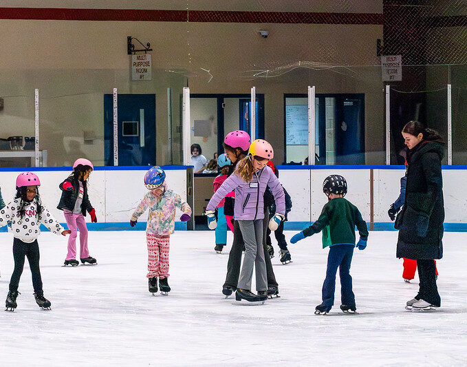Youth ice skaters in a group class with a coach
