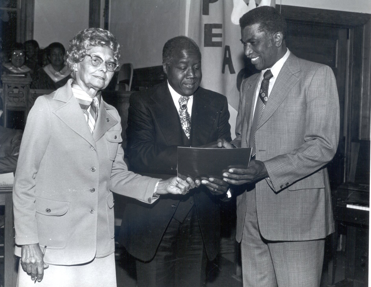 A black and white photo showing Edith Throckmorton with an unknown man and R. Silas Craft. All three are in business attire and appear to be taking part in an awards presentation or similar event.