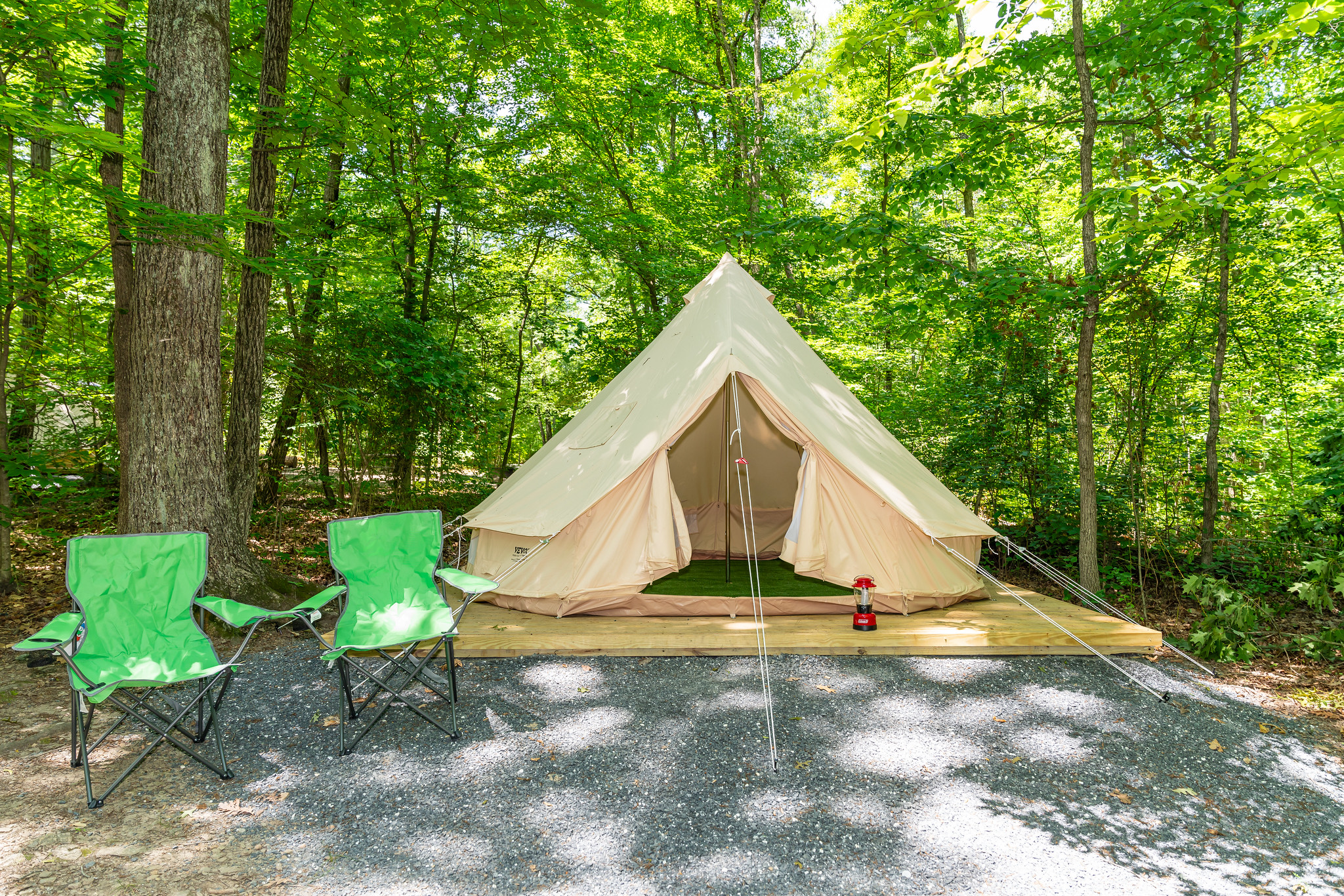 White canvas camping tent with two green camping chairs in a wooded area at Little Bennett Campground