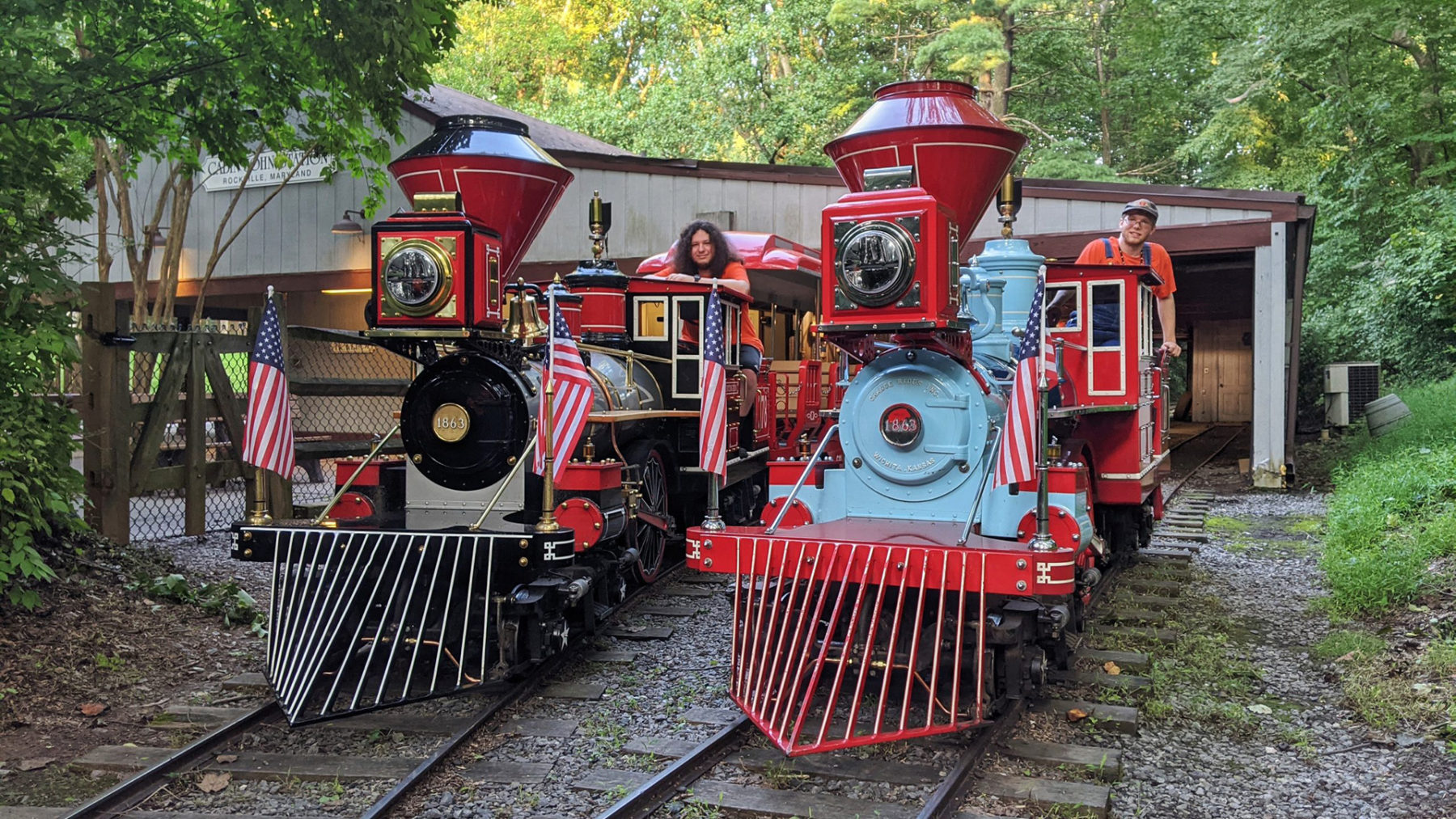 Two miniature trains with conductors