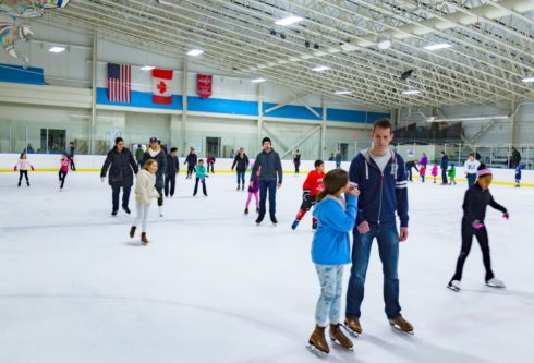 Adults and children on the ice at a public skating session.