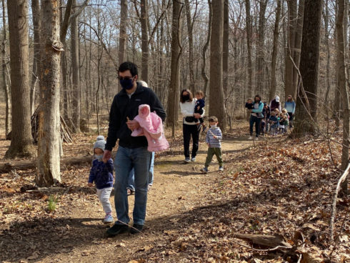 Adults with small children hiking on a natural surface trail.
