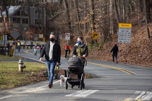 Two adults walking a stroller and dog on Open Parkways.