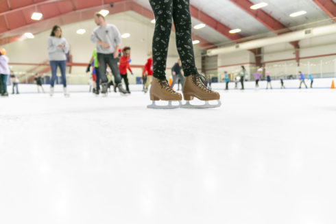 Closeup shot of a person’s feet wearing ice figure skates while skating at one of our public skating sessions at our indoor ice centers.