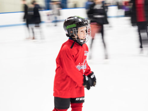 Boy skating on indoor ice rink wearing a Washington Capitals jersey.