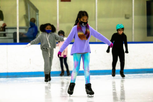 Three girls skating on indoor ice rink.