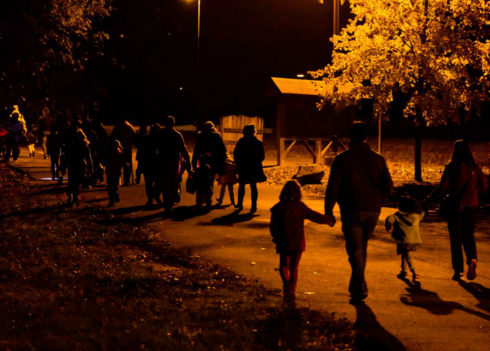Adults and children on a night hike in a park.