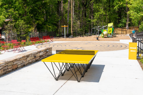 The newly-renovated Edith Throckmorton Neighborhood Park with a playground, yellow metal ping pong table, and red metal tables and chairs.
