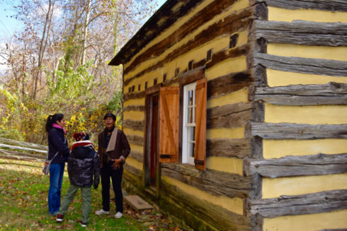 A guide talks to a parent and child outside the historic Oakley Cabin.