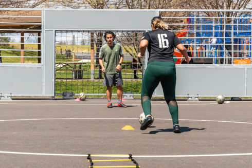 two people playing soccer on a futsal court