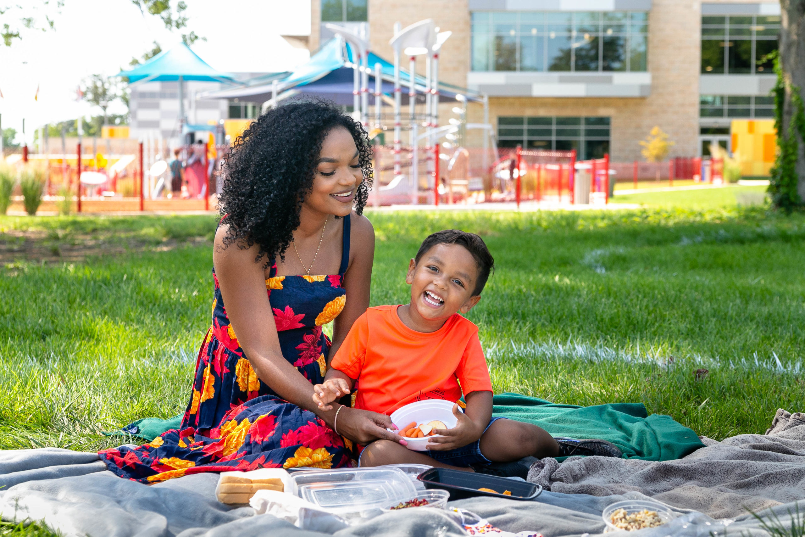 Mother and son smiling having a picnic on grass