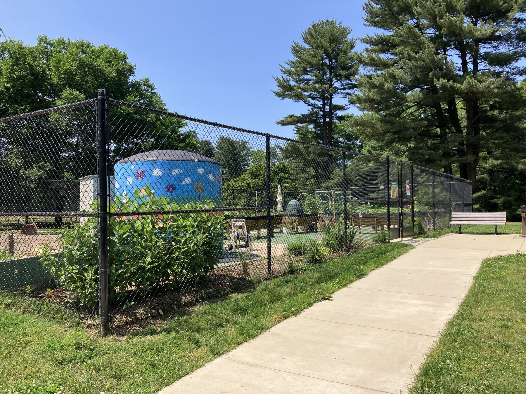 view of Nolte Community Garden from outside of the fence, showing the painted cistern and flowers