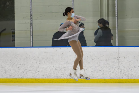 An ice skater jumps into the air during a figure skating performance at one of Montgomery Parks' indoor ice rinks.