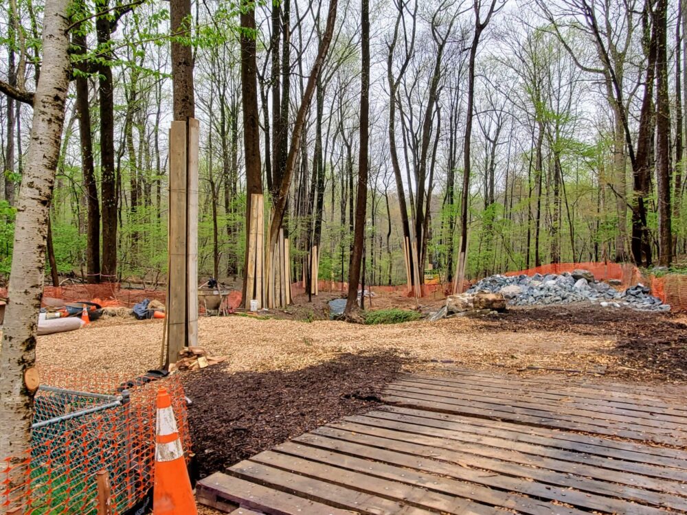An access path for equipment and materials for a stream restoration project. The image shows mulch and wood chips laid down, along with tree protection around mature trees.