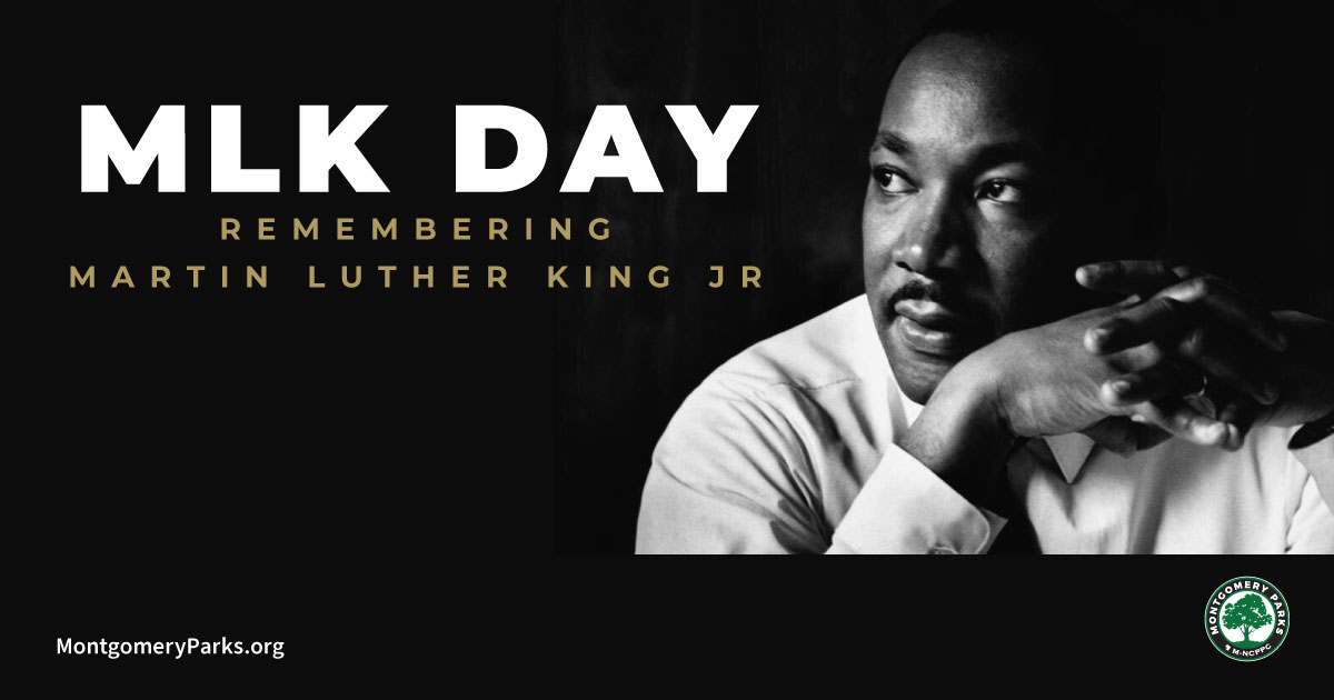 Black and white photograph of Dr. Martin Luther King, Jr. He leans forward and has his hands in front of him with interlocking fingers. He looks off to the side in thought. Text reads: MLK Day. Remembering Martin Luther King, Jr.