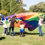 group of adults and kids with rainbow parachute