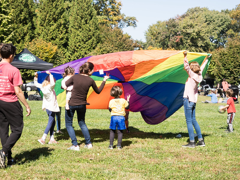 group of adults and kids with rainbow parachute