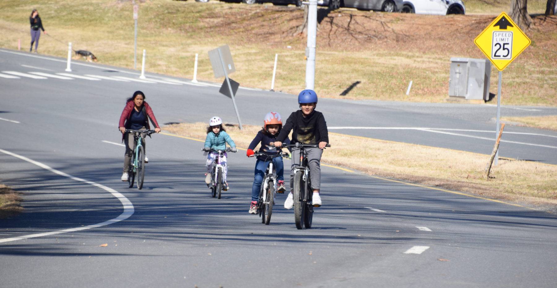 Four visitors riding their bikes on Open Parkways road.