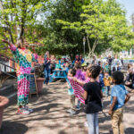 Several little kids ages three through six dancing along with Ms. Niki as she sings to them at Takoma Urban Park