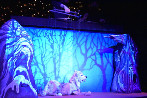 puppeteers controlling the marionette wolf puppet in a night landscape in peter and the wolf