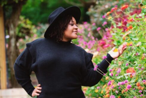 Vanessa Pierre in a garden, looking at and holding flowers. 