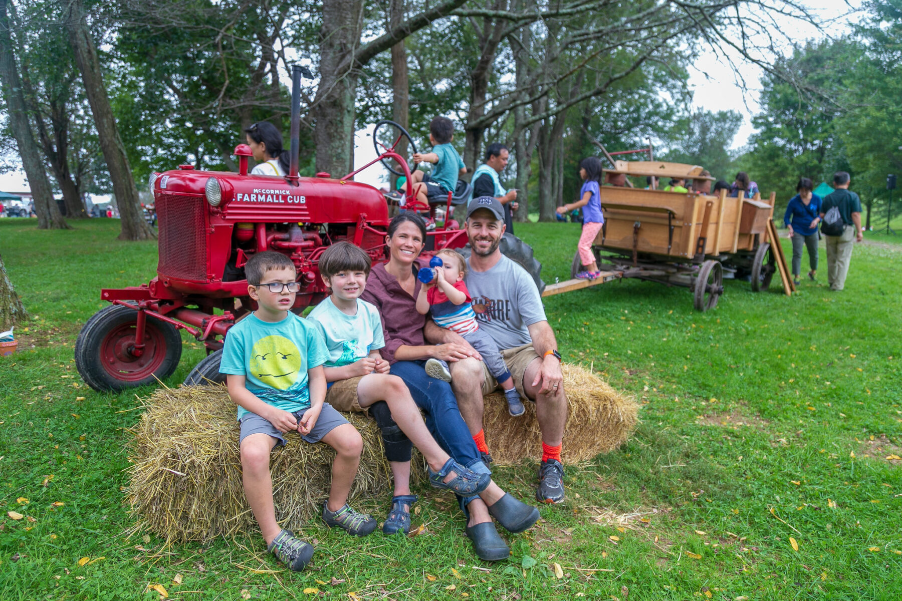 Family smiling sitting on hay at Ag History Farm Park