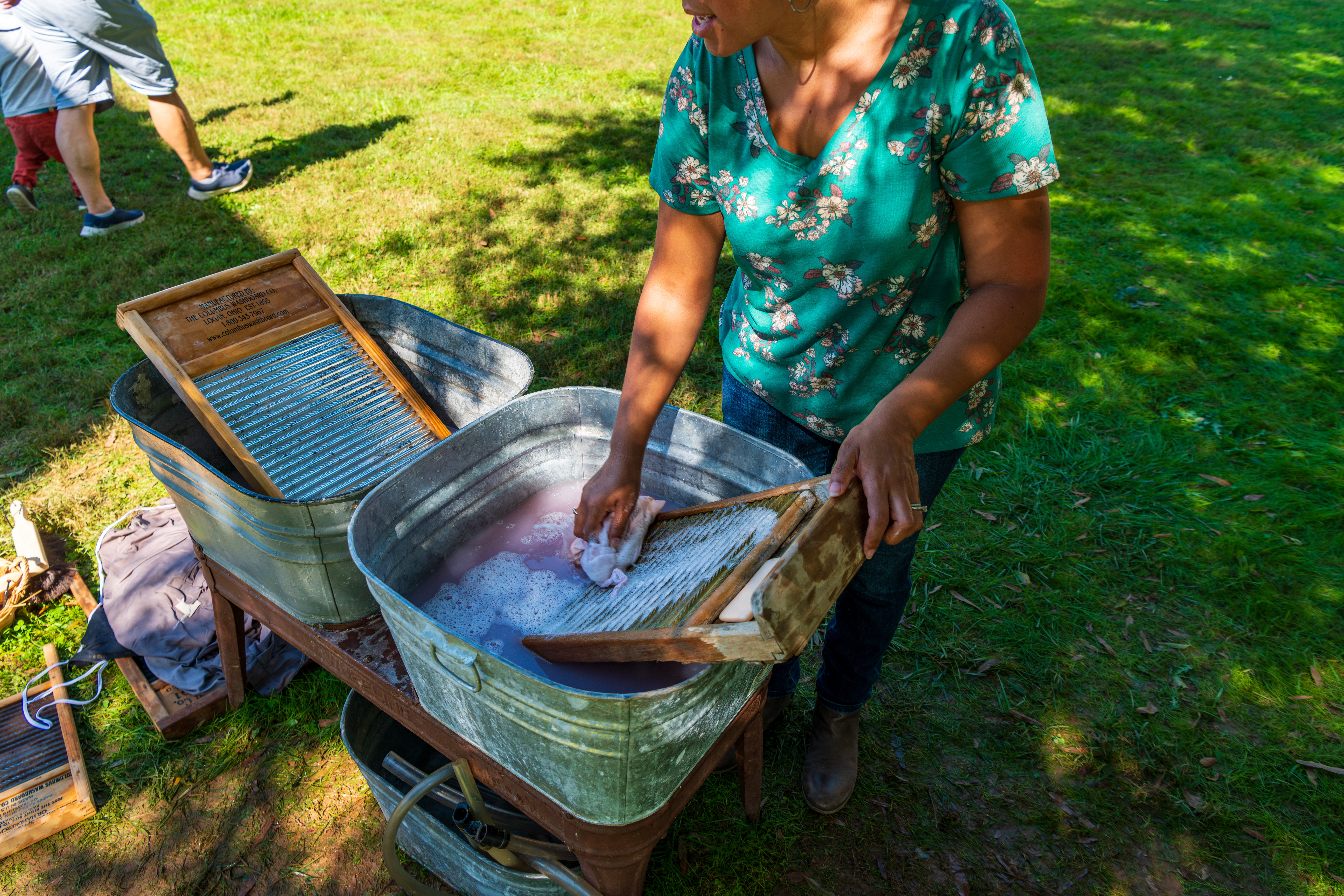 Woman washing a shirt in an old aluminum bin