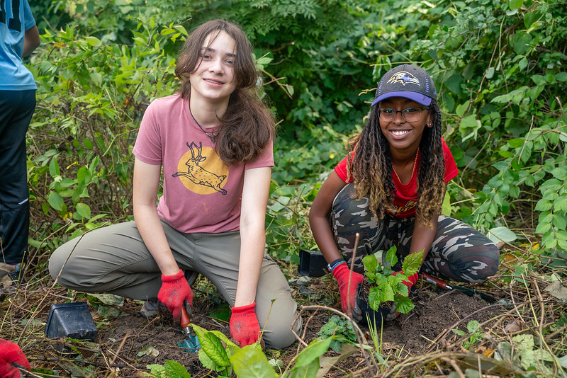 two young teens planting plants in the soil