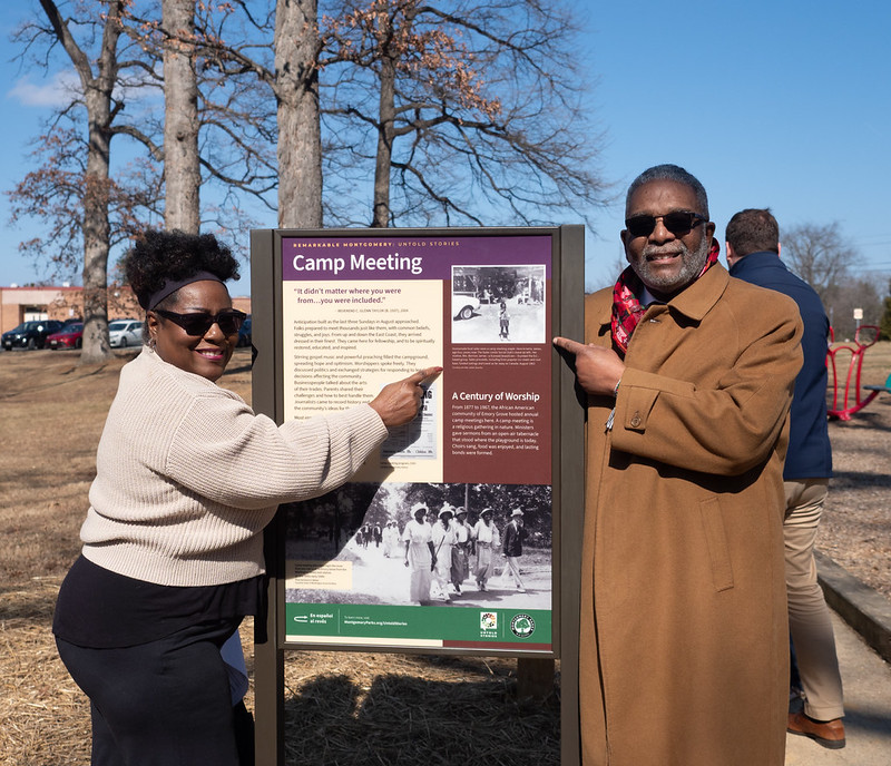Two people standing by sign
