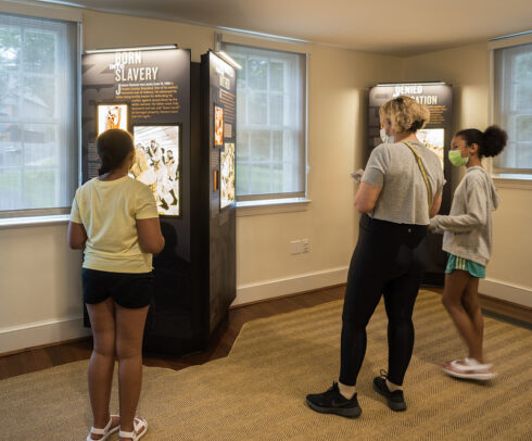 Three visitors look at exhibits inside the Josiah Henson Museum
