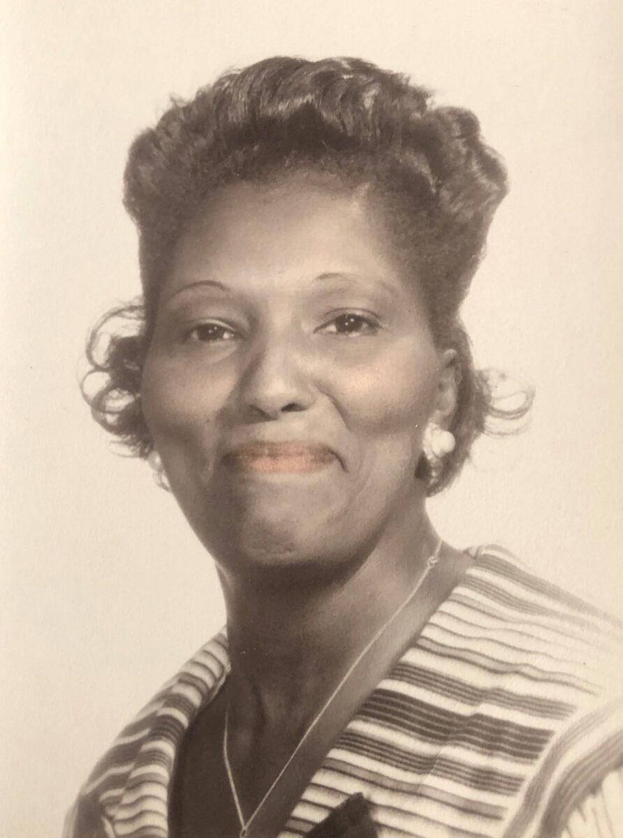 Colorized photo of Mildred Pumphrey in 1957. She's smiling and wearing a striped shirt.