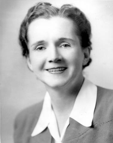 Black and white photograph of Rachel Carson. She is wearing a white-collared shirt and has her hair back. She is smiling.