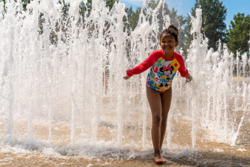 A youth stands next to a water feature